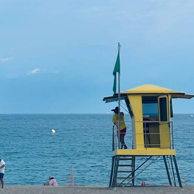 Geel strandwachthuisje aan een blauwe zee